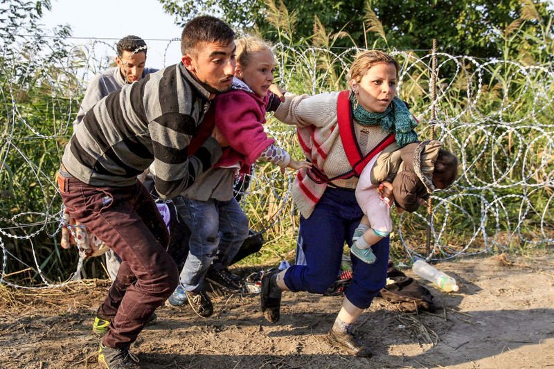 Uprchlíci překračující plot